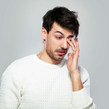 Image shows woman looking up putting eye drop in eye